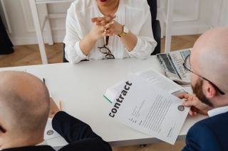 Deux personnes annotent un contrat imprimé posé sur une table