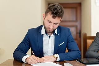 Deux personnes annotent un contrat imprimé posé sur une table